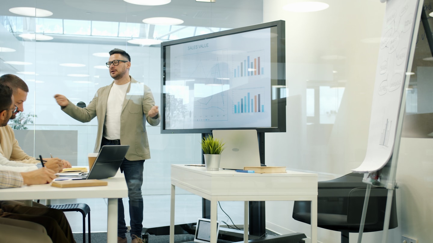 Man presenting data on a large screen to colleagues Man presenting data on a large screen to colleagues