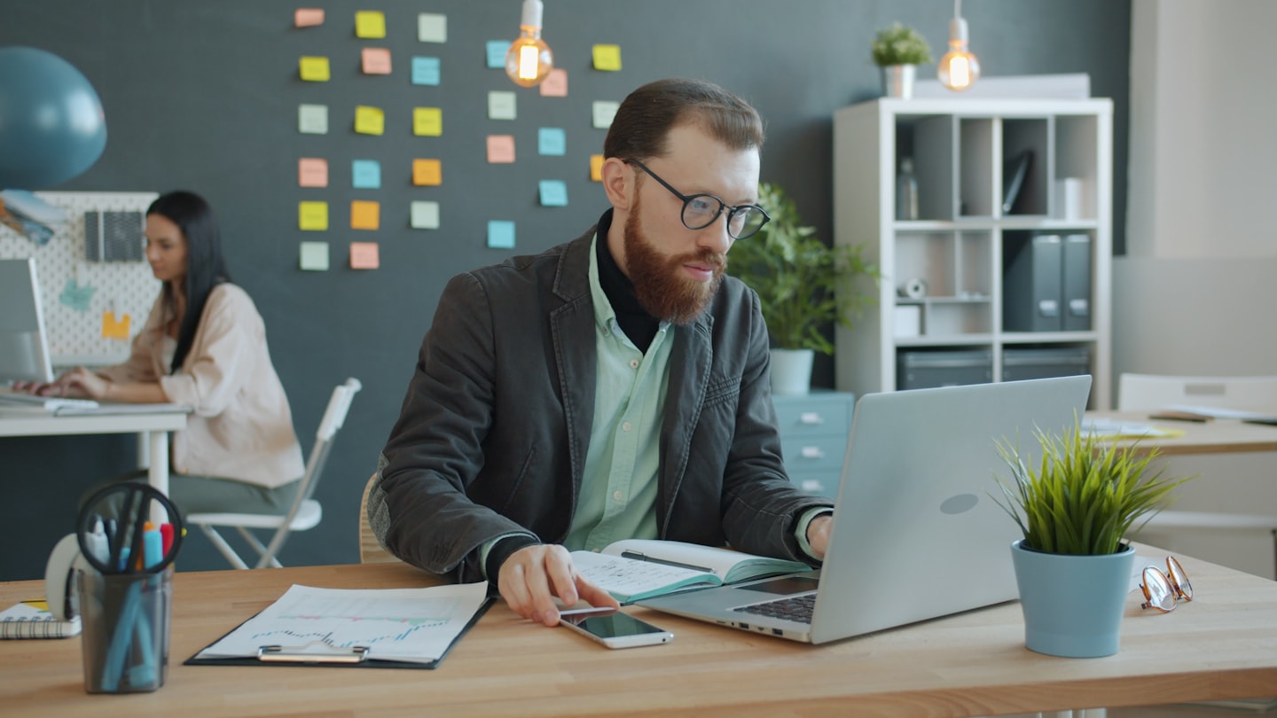 Man working on laptop in modern office with sticky notes