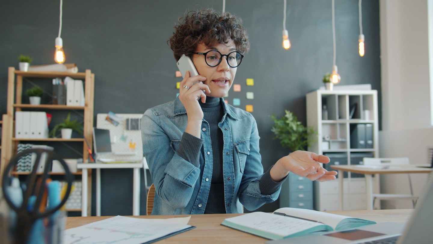 Woman talking on phone at desk in office Woman talking on phone at desk in office
